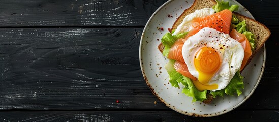 Poster - Copy space image featuring a poached egg and salmon on lettuce atop toast bread for breakfast set against a sleek black wooden backdrop