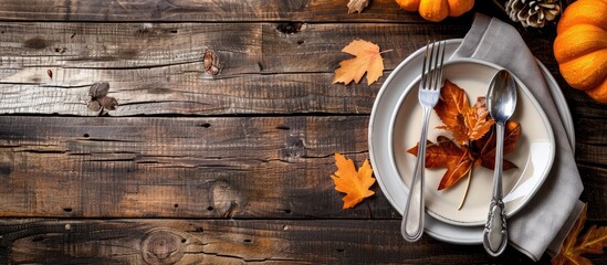 Poster - Autumn themed plate silverware in a napkin with fall decor on a wooden background ideal for Thanksgiving or autumn related content Copy space image available