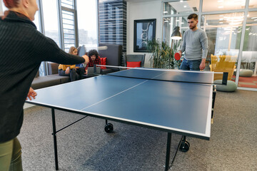  Business colleagues take a break from work to enjoy a game of table tennis, fostering teamwork and camaraderie in the workplace