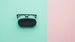 © VK Studio - A pair of eyeglasses resting on a black case, elegantly placed against a two-tone pastel background of mint and pink.