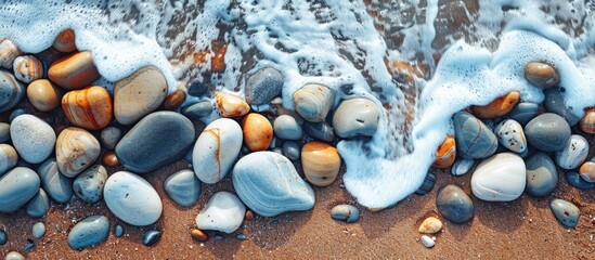 Top view of stones on the beach with ocean waves, providing a textured backdrop for a copy space image.