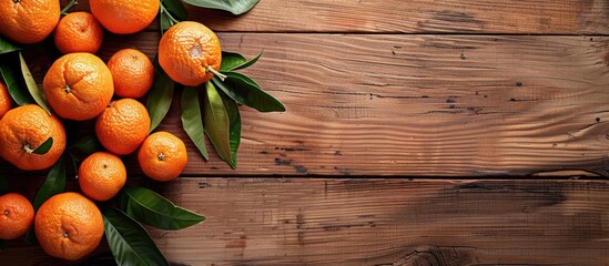 Wall Mural - Fresh mandarin oranges displayed with leaves on a wooden table, providing a copy space image.