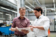 © Westend61 - Business colleagues discussing strategies over tablet PC standing in factory