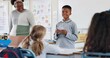 © Nina2024/peopleimages.com - Class, happy kid and reading presentation for education, learning or knowledge in elementary school. Boy child, students and speech with teacher for robotics assignment project with paper in lesson