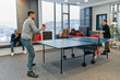 © .shock - Business colleagues take a break from work to enjoy a game of table tennis, fostering teamwork and camaraderie in the workplace