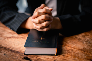 Wall Mural - Hands folded in prayer on a Holy Bible in church concept for faith, spirituality and religion, woman praying on holy bible in the morning. woman hand with Bible praying.