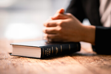 Wall Mural - Hands folded in prayer on a Holy Bible in church concept for faith, spirituality and religion, woman praying on holy bible in the morning. woman hand with Bible praying.