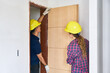 © Robert Kneschke - Young male and female construction workers wearing safety workwear installing door at incomplete house