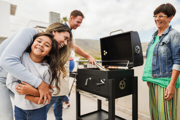 Poster - Family people doing barbecue at home's rooftop - Happy multiracial friends having fun eating and cooking together during weekend day - Summer and food concept - Main focus on kid face