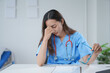 © amnaj - Female doctor is feeling exhausted and stressed while sitting at her desk at the hospital