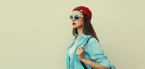 Wall Mural - Stylish young girl in baseball cap, glasses, modern teenager girl looking away on white background