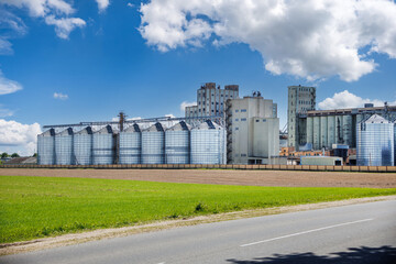 Wall Mural - modern granary elevator with silver silos on agro-processing and manufacturing plant for processing drying cleaning and storage of agricultural products, flour, cereals and grain.