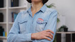 © Synthex🇺🇦 - Serious woman with a vote pin standing at an election place, arms crossed on her chest