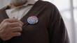 © Synthex🇺🇦 - Senior man wearing a vote badge on election day, citizen showing civil position
