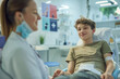 © lenblr - A teenager happily donates blood at a clinic, supported by healthcare professionals. The process is wellassisted, ensuring a positive experience for the youth
