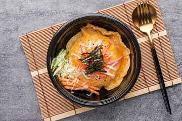 Korean style scrambled eggs on rice in a black bowl topped with seaweed, crab sticks, ready to eat