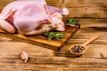 Wall Mural - Wooden cutting board with the whole uncooked chicken, garlic and spices