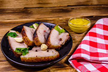 Wall Mural - Slices of baked pork belly, garlic and parsley on a black plate