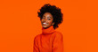 © Porechenskaya - Smiling young happy woman in orange sweater on one tone background. Positive fall winter concept.