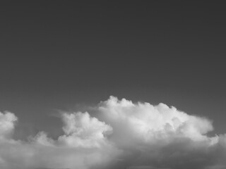 Summer white fluffy cumulus clouds in the deep blue sky. Black and white monochrome grayscale photo