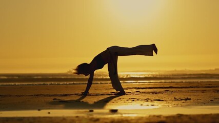 Wall Mural - A woman is doing martial gymnastic on the beach with her hair blowing in the wind