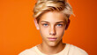 © ALA - Portrait of a happy serious blond haired confident teenage guy with perfect skin, orange background, banner.