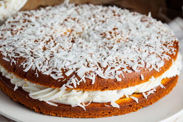 a white plate with a cake and coconuts. sweet fresh breakfast concept. a large cake with coconuts on