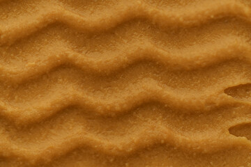 Brush texture of brown peanut paste in waves. The concept of smear on bread, natural nut desserts