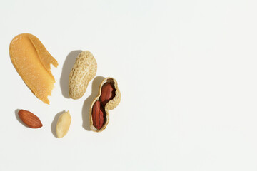 Smear texture of brown peanut paste and whole peanuts on a white isolated background. Concept of protein snacks, natural sweets. Background for your banner design