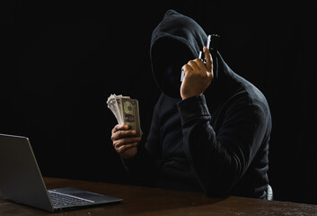 Portrait hacker spy man one person in black hoodie sitting on table looking computer laptop used login password attack security to data digital internet network system night dark background copy space