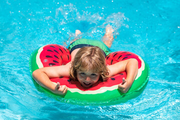 Wall Mural - Child swim in summer pool water. Happy kid playing with colorful swim ring in swimming pool on summer day. Child water vacation. Children play in tropical resort.