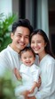© Stone Story - Happy family portrait with smiling parents and baby. Outdoor setting with greenery, casual white clothing, sunlight and joy captured.