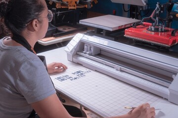 Young woman removes excess material with weeding tool, cutting plotter workplace.