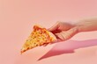 © LidiaLens - A hand holding a slice of cheese pizza against a soft pink background in bright lighting