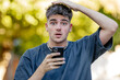 © carballo - young man or teenager on the street with mobile phone and surprised expression