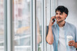 © carballo - young man with mobile phone and cup at home window
