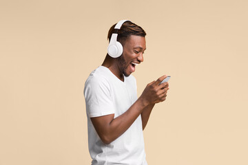 Aufkleber - Mobile Games. Excited Black Man In Wireless Headphones Using Smartphone Over Yellow Background In Studio