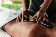 © David Prado/Stocksy - Hot stone massage therapy session at a spa