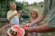 © Anna Artemenko/Stocksy - father cuts watermelon for children