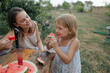© Anna Artemenko/Stocksy - woman with little daughter eating watermelon