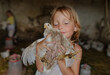 © Anna Artemenko/Stocksy - portrait of a girl with a chicken in her hands