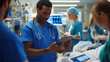 © AndyGordon - Emergency room doctors and nurses discussing a critical case over a tablet in a busy ER environment