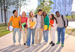 © CarlosBarquero - Group of generation z international university students laughing standing hugging together on campus garden. Young diverse people looking smiling at each other holding backpacks and workbooks outdoors
