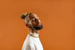 © Andrii - Confident black gay man with bright makeup standing isolated on orange background, dressed white. Exudes sense of pride and individuality. Diversity power of personal style. Closed eyes