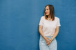© Olga Moreira/Stocksy - Woman in casual clothing standing against blue wall