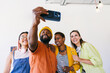 © VICTOR TORRES/Stocksy - Multi-ethnic friends taking a selfie at a casual gathering with drinks