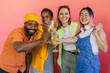 © VICTOR TORRES/Stocksy - Diverse friends toasting with champagne against a pink background.