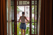 © Alvaro Lavin/Stocksy - Tourist admiring city view from her hostel room balcony in thailand
