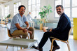 © BONNINSTUDIO/Stocksy - Two businessmen smiling during a meeting in a modern office