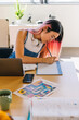 © VICTOR TORRES/Stocksy - Focused chinese young woman studying at desk with laptop and planner